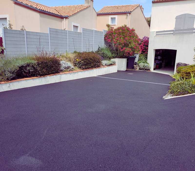 Cour et accès de maison réalisés en enrobé noir pour aménagement extérieur