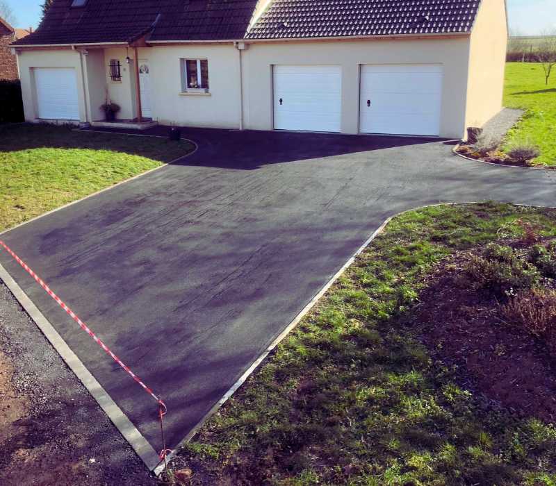 Allée goudronnée devant garage avec revêtement en enrobé bitumeux